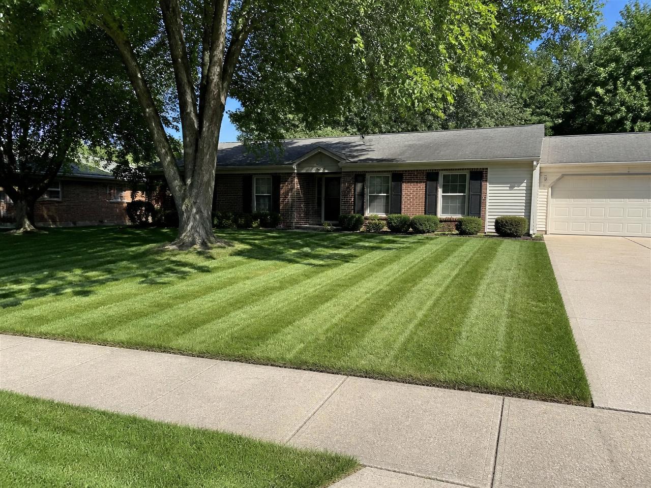 Crew mowing precise stripes into a residential lawn